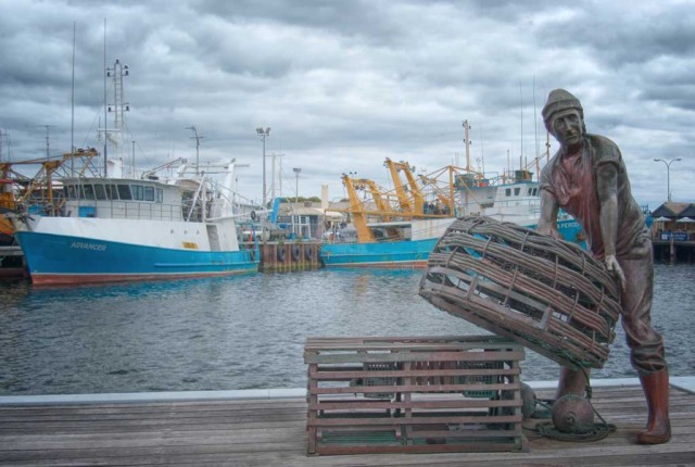 Bronze statue of a fisherman stacking baskets at Fremantle Fishing Boat Harbour