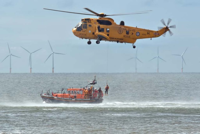 RNLI Lifeboat and Royal Air Force Rescue Helicopter practice transferring rescued person from helicopter to lifeboat